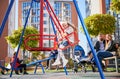 Little girl swinging with parents behind. Royalty Free Stock Photo