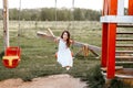 Little girl is swinging at a playground when the sun is setting. Happiness concept Royalty Free Stock Photo