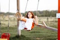 Little girl is swinging at a playground when the sun is setting. Happiness concept Royalty Free Stock Photo