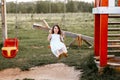 Little girl is swinging at a playground when the sun is setting. Happiness concept Royalty Free Stock Photo