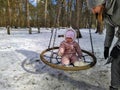 Little girl swinging on swing in snowy forest Royalty Free Stock Photo