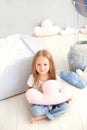 A little girl in a T-shirt and jeans holds a cloud pillow against the background of a decorative balloon. Toddler is playing in th Royalty Free Stock Photo