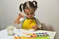 A little girl at the table draws on her fingers Royalty Free Stock Photo