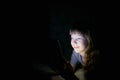 Little girl with a tablet on the bed at night. Royalty Free Stock Photo