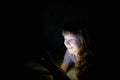 Little girl with a tablet on the bed at night. Royalty Free Stock Photo