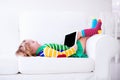 Little girl with tablet computer on a white couch Royalty Free Stock Photo