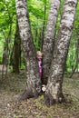 Little girl with tails hiding behind the trunk of birch Royalty Free Stock Photo