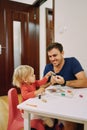 Little girl takes a plasticine figurine from her father hand while sitting at the table Royalty Free Stock Photo