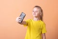 Little girl takes a selfie, on a light orange background