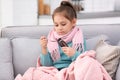 Little girl taking cough syrup on sofa Royalty Free Stock Photo