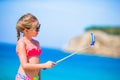 Little girl taking selfie by her smartphone on the beach. Kid enjoying her suumer vacation and making photos for memory Royalty Free Stock Photo