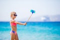 Little girl taking selfportrait by her smartphone on the beach. Kid enjoying her suumer vacation and making photos for Royalty Free Stock Photo