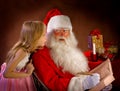 Little Girl Talking to Santa Clause While He Writes Magic Feathe Royalty Free Stock Photo