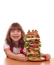 Little girl with tall sandwich on table