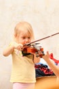 A little girl is taught to play the violin and is helped to hold the instrument correctly