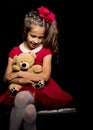 Little girl with a teddy bear on a black background. Royalty Free Stock Photo