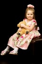 Little girl with a teddy bear on a black background. Royalty Free Stock Photo