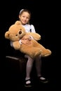 Little girl with a teddy bear on a black background. Royalty Free Stock Photo