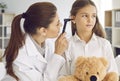 Otolaryngologist examining child's ear with otoscope during checkup at her office