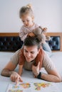 Little girl with a teddy bear sits on the shoulders of her dad reading a book of fairy tales while lying on his stomach Royalty Free Stock Photo