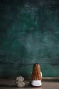 Little girl with teddy bear sitting on floor in empty room. Autism concept Royalty Free Stock Photo