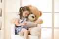 Little girl with Teddy bear watching her tablet computer