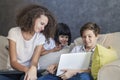 Little girl, teen boy and curly hair girl wirh laptop on sofa a Royalty Free Stock Photo