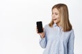 Little girl, teen child showing smartphone screen, mobile phone app display, smiling and looking happy at camera Royalty Free Stock Photo