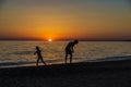 Little girl and teenager playing on a beach at sunset Royalty Free Stock Photo