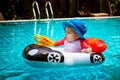 A little girl less than one year old is driving an inflatable boat in the shape of a car. She is surprised to touch the steering Royalty Free Stock Photo