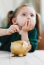 Little girl thinking about her money spending and putting a coin into a piggy bank. Money saving and deposit concept Royalty Free Stock Photo