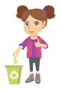 Little girl throwing banana peel in recycling bin.