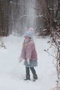 A little girl throws snow in the forest.