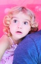 A little girl of toddler age, looking on in wonderment whilst cuddling up to a parent. Royalty Free Stock Photo