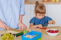 Little girl toddler cutting strawberry near her mother