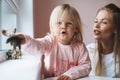 Little girl toddler with her mother playing with animal toys on window sill in children`s room at home Royalty Free Stock Photo