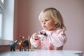 Little girl toddler in pink playing with animal toys on table in children`s room at home Royalty Free Stock Photo