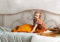 A little girl todler cheerfully plays with pillows on the bed in the children`s bedroom. Adorable kid at home, family lifestyle Royalty Free Stock Photo