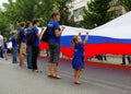 Little girl together with other activists hold a large Russian flag on the Independence day of Russia in Volgograd