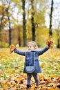 Little girl tossing leaves in autumn park