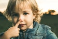 Little girl touching her nose with a finger