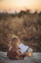 Little Girl with toy reading the book on rural landscape, toned image. Royalty Free Stock Photo