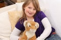 Little girl with toy tiger on sofa Royalty Free Stock Photo