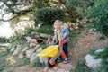 Little girl with a toy wheelbarrow going down the hill in the park Royalty Free Stock Photo