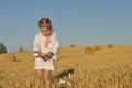 A little girl in a traditional chemise standing barefoot in a harvested field with ears in her hand Royalty Free Stock Photo