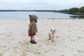Little girl trains her puppy at the beach in autumn. A child plays with her small bulldog Royalty Free Stock Photo