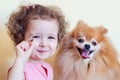 Little girl trains pomeranian spitz. beautiful little baby with curls gives to fluffy dog food, yummy. pet obedience. happy childh Royalty Free Stock Photo