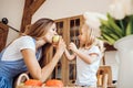 Little girl treats her mother to an apple at the kitchen