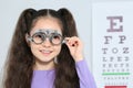 Little girl with trial frame near eye chart in hospital Royalty Free Stock Photo