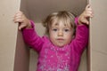 A little girl tries to get out of a cardboard box. Concept: children`s fears and emotions, complexes and resentments